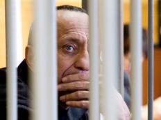 Mikhail Popkov looks through bars during a court session in Irkutsk, Russia, Monday, Dec. 10, 2018.  A court in Russia's eastern Siberia on Monday  convicted Popkov, a former policeman of murdering 56 women, bringing the number he is believed to have killed to at least 78. (Julia Pykhalova, Komsomolskaya Pravda via AP)