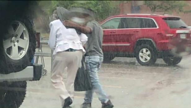 Tyrea helping shield woman from rain [Independence Police Department]