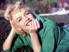 Actress Marilyn Monroe poses for a portrait laying on the grass in 1954 in Palm Springs, California.