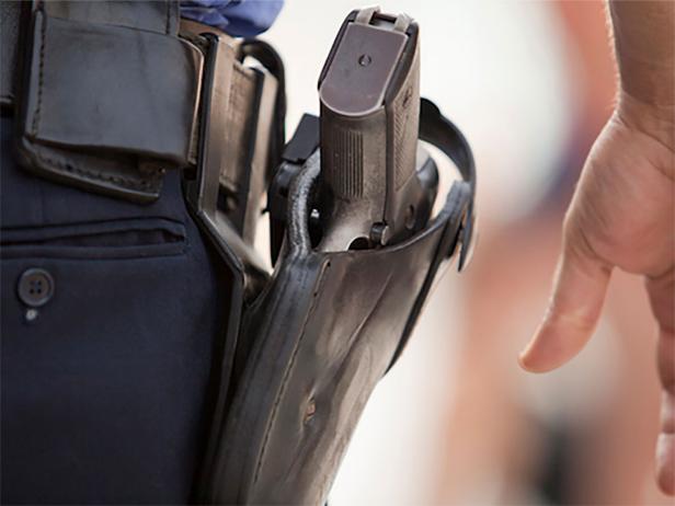 A policeman with his hand close to his gun [iStockPhoto]