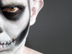 face painted with a skull. The photo shows a young man with painted face face painted with a skull.