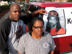 Kenneth and Jacquelyn Johnson stand next to a banner on their SUV showing their late son, Kendrick Johnson in Valdosta, Ga. in 2013 [via AP Images]