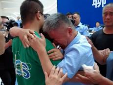 Guo Gangtang (right) embraces his long lost son Guo Xinzhen (left) during a reunion after 24 years in Central China. [screenshot via CCTV]