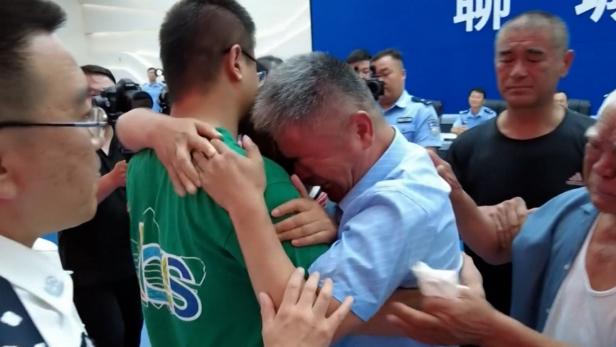 Guo Gangtang (right) embraces his long lost son Guo Xinzhen (left) during a reunion after 24 years in Central China. [screenshot via CCTV]