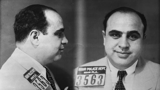 A black and white mug shot of Al Capone wearing a suit and tie.
