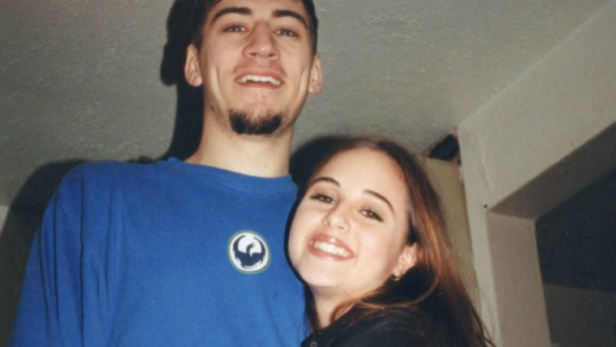 (L-R) Anthony Cooper wearing a blue t shirt and Melinda Hotkins hugging Anthony both smiling in front of a white wall