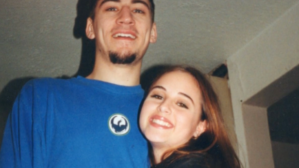 (L-R) Anthony Cooper wearing a blue t shirt and Melinda Hotkins hugging Anthony both smiling in front of a white wall