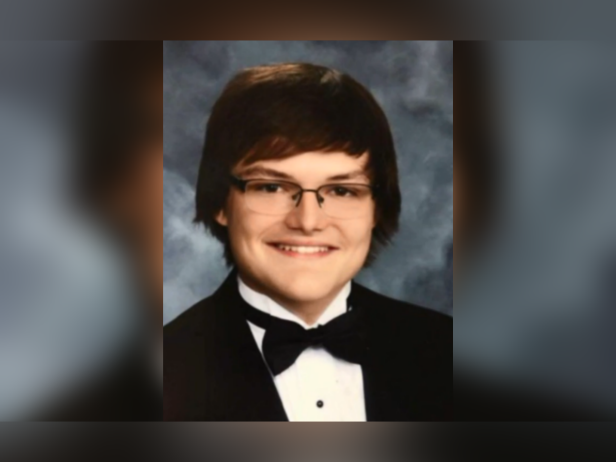 Thomas Brown smiling in front of gray background professional photo wearing glasses short brown hair bowtie tux