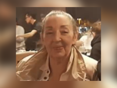 Karen Navarro smiles at the camera. She is wearing a tan jacket over a white shirt and appears to be seated at a restaurant table.