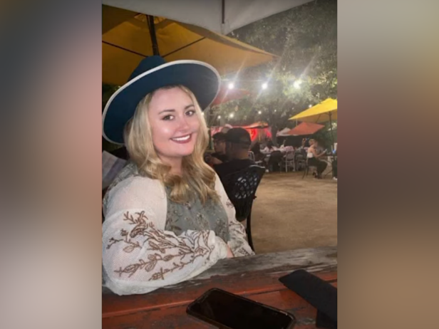 Ciaya Whetstone is a white female with blonde hair. In this photo she is wearing a top with white sleeves and a black wide-brimmed hat