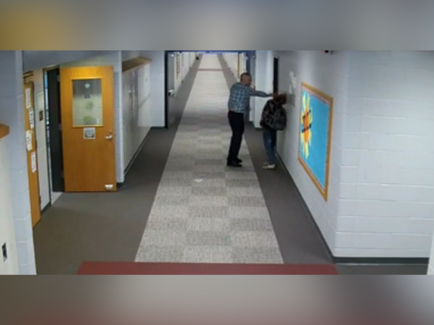 The image is of a teacher striking a student in the head in the hallway of a school.