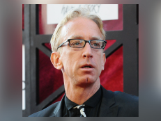 Actor Andy Dick was arrested in May 2022 on felony sexual battery charges after a man alleged the comedian molested him. Dick is shown wearing a black suit with a black and white tie.