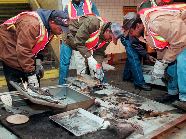 Transit workers dismantle the charred inner wall of a token booth at the Kingston Avenue and Fulton Street subway station in the Bedford-Stuyvesant section of Brooklyn, Nov. 26, 1995, after attackers sprayed a flammable liquid into the token booth and lit it on fire, according to police.