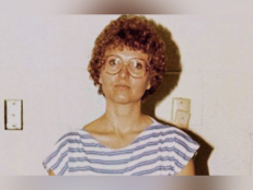 A photograph of Candy Montgomery. She has curly brown hair and round brimmed glasses. She wears a blue and white horizontal shirt.