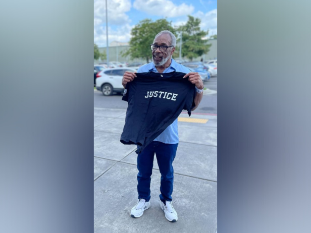 Larry Moses stands holding a shirt that says "Justice".